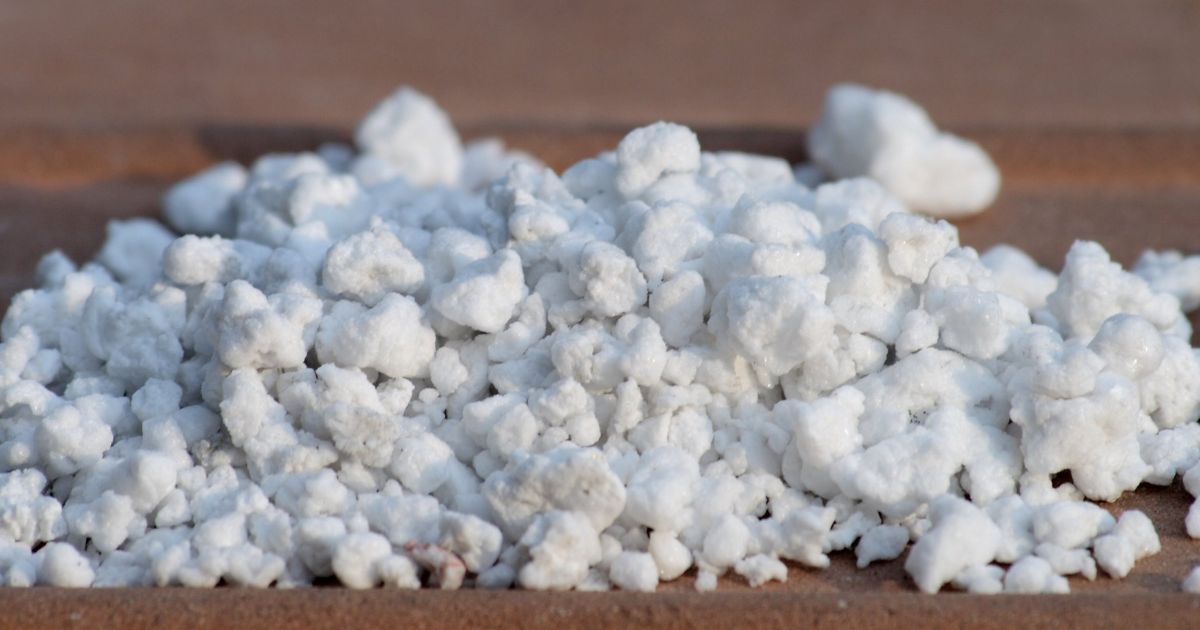 A close-up image of a pile of white, granular material, resembling perlite or a similar substance, often used in gardening and horticulture for soil aeration and drainage. The granules are irregularly shaped and vary in size, creating a textured appearance.