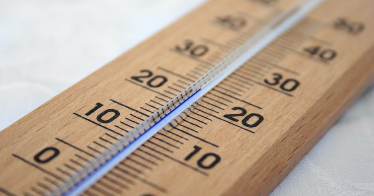 Close-up of a wooden thermometer showing temperatures in Celsius, with markings from 0 to 40 degrees.