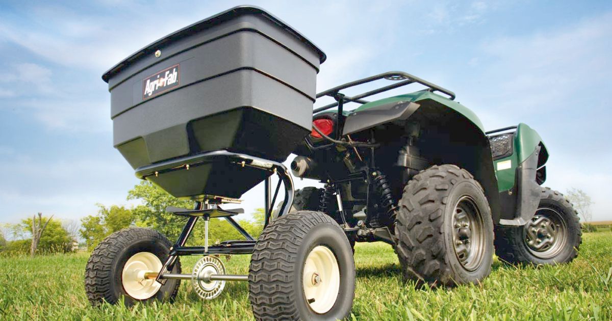 An ATV equipped with an Agri-Fab ATV tow spreader, ideal for efficient and even fertilizer distribution.